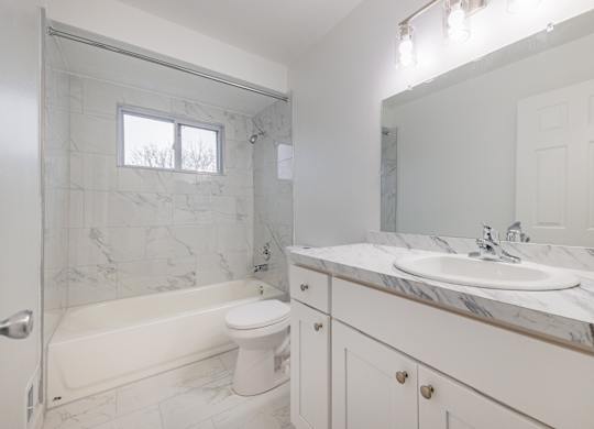 A white bathroom with a marble counter top and a tub.