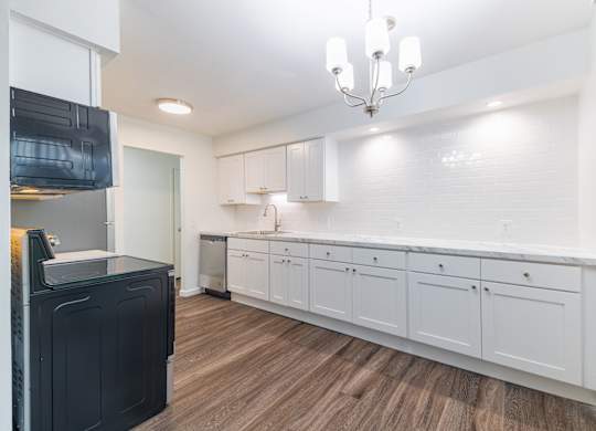 A kitchen with white cabinets and a black fridge.