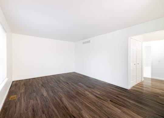 A room with wooden flooring and white walls.
