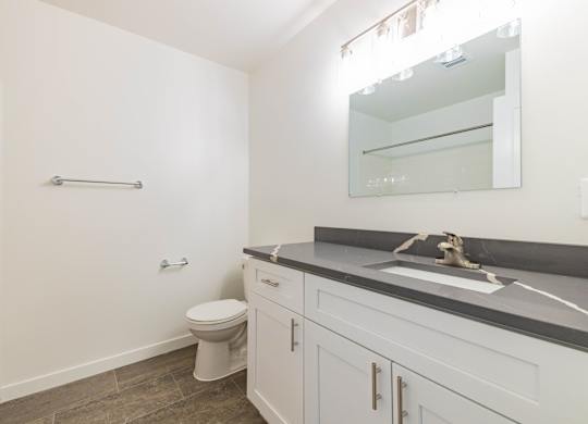 A white bathroom with a toilet, sink, and mirror.