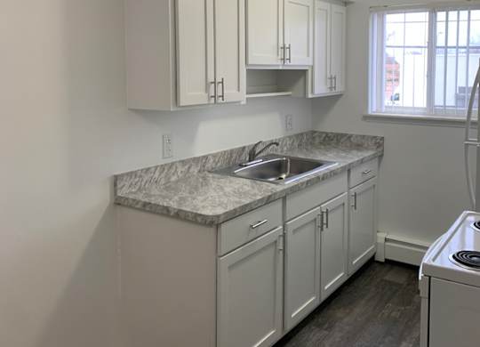 A kitchen with white cabinets and a marble countertop.