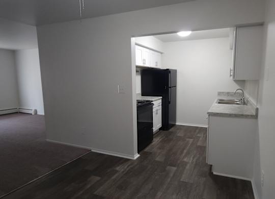 A kitchen area with a refrigerator, sink, and cabinets.