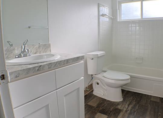 A white bathroom with a marble sink and toilet.