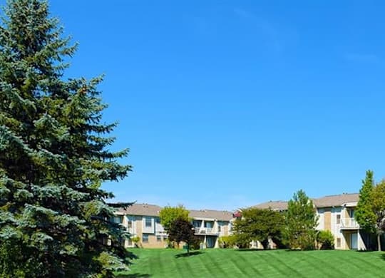 an apartment building with a green lawn and trees