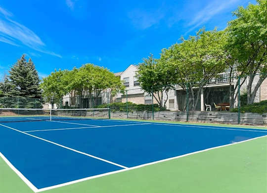 a blue and green tennis court in front of a house