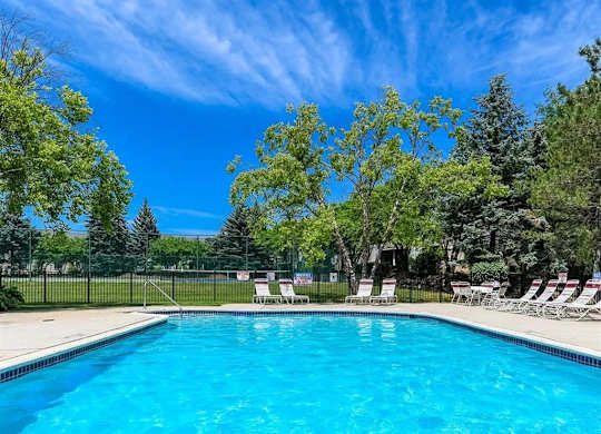 a swimming pool with chairs and trees next to it