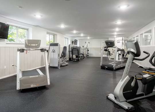 A gym with a variety of exercise equipment including treadmills, stationary bikes, and weight machines.