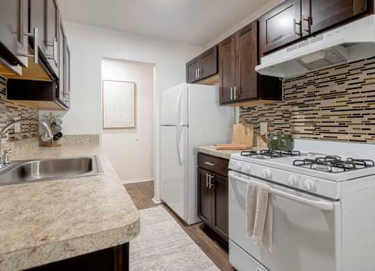 A kitchen with a white stove top oven and a white refrigerator.