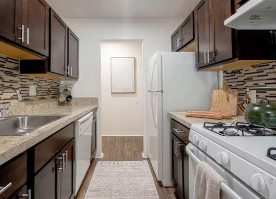 A kitchen with a white refrigerator, white oven, and a white sink.