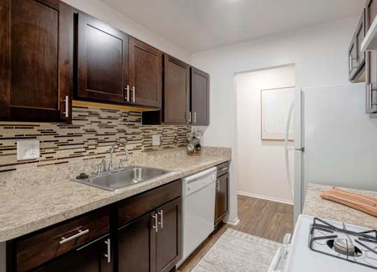 A kitchen with a white stove top oven and a white dishwasher.