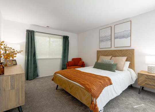 A bedroom with a bed, nightstand, and a window with curtains.