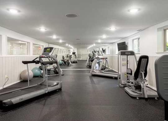 A gym with treadmills, elliptical machines, and other exercise equipment.