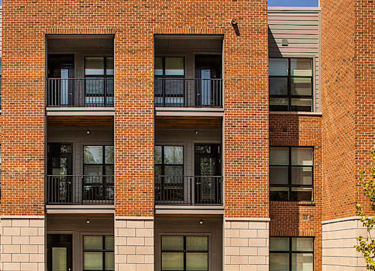 A red brick building with balconies and windows.
