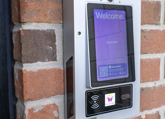 A brick wall with a door and a digital screen on it.