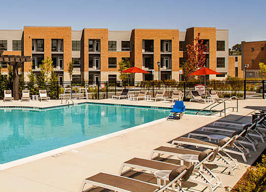 A large swimming pool surrounded by sun loungers and umbrellas.