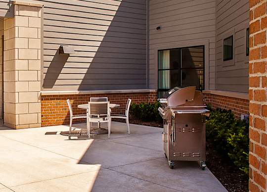 A patio with a table and chairs is outside a house.