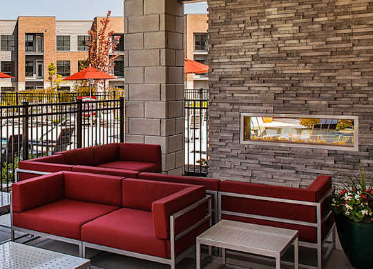 A patio with red chairs and a pool in the background.