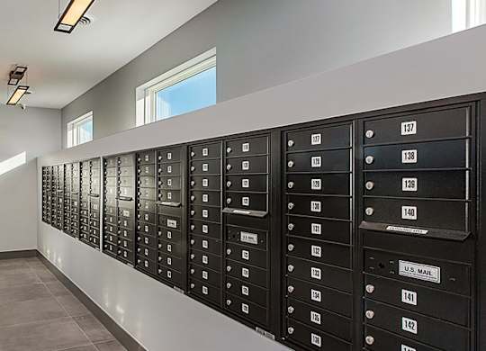 A long hallway with black mailboxes on the wall.