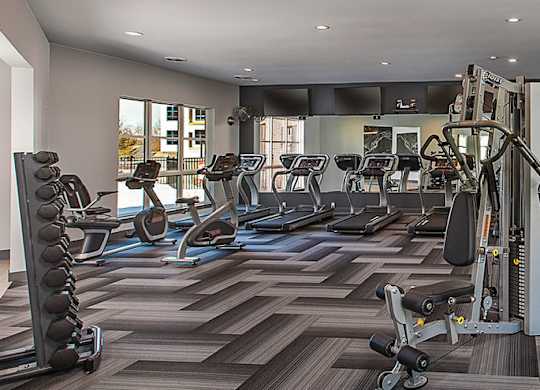 A gym with a variety of equipment including treadmills, weights, and exercise machines.