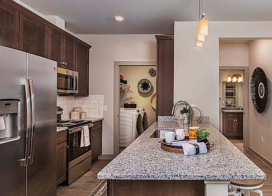 A kitchen with a granite counter top and stainless steel appliances.