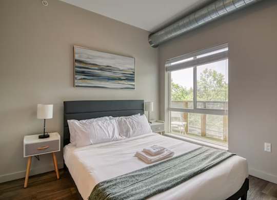 A bedroom with a large bed and a painting on the wall.