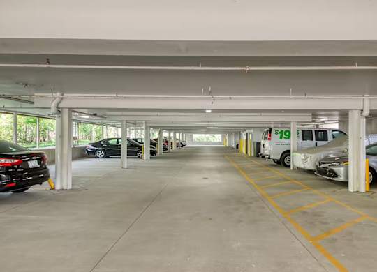 A parking garage with a white van and a black car.
