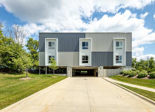 A modern house with a grey exterior and white windows.