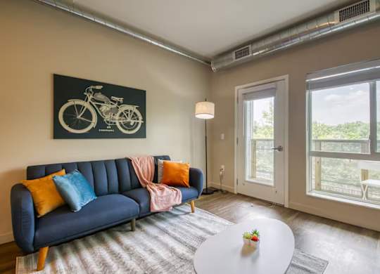 A living room with a blue couch and a bicycle picture on the wall.