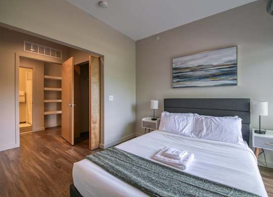 A bedroom with a large bed and a painting on the wall.