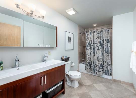 A bathroom with a white sink, toilet, and a shower curtain with letters on it.