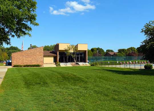 A building with a flag on top is surrounded by a green lawn.