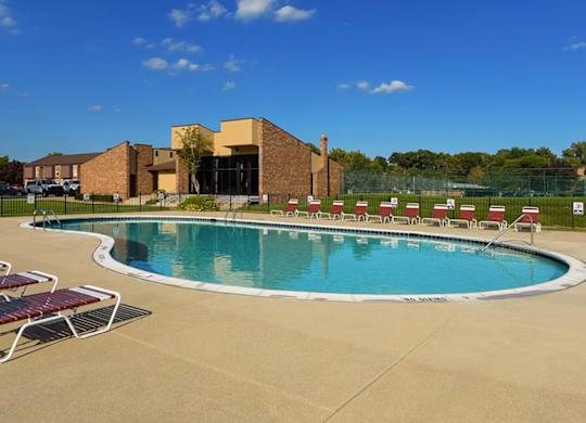 A large outdoor swimming pool with sun loungers and a building in the background.