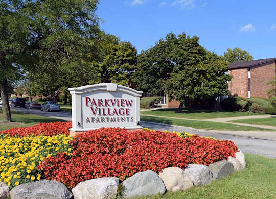 A sign for Parkview Village Apartments is surrounded by a flower bed.