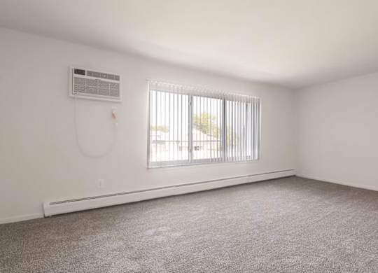 A room with a window covered by blinds and an air conditioner on the wall.