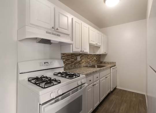 A kitchen with white cabinets and a white stove top oven.