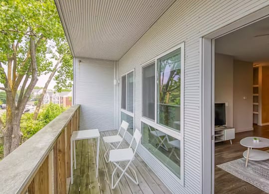 A balcony with a table and chairs overlooking a tree.