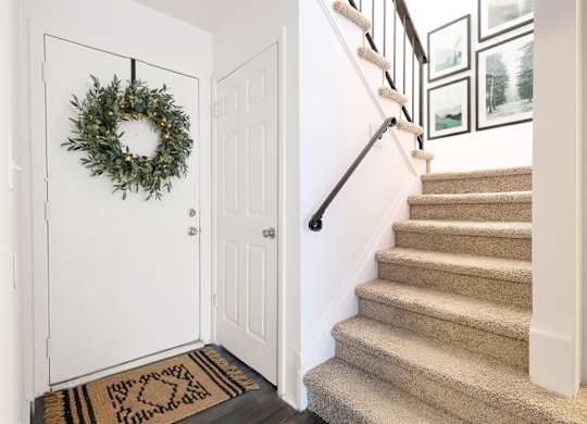 A white door with a wreath on it and a staircase.