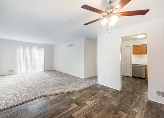 A room with a ceiling fan and wooden flooring.