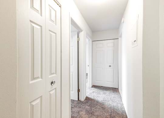 A hallway with white doors and a carpeted floor.
