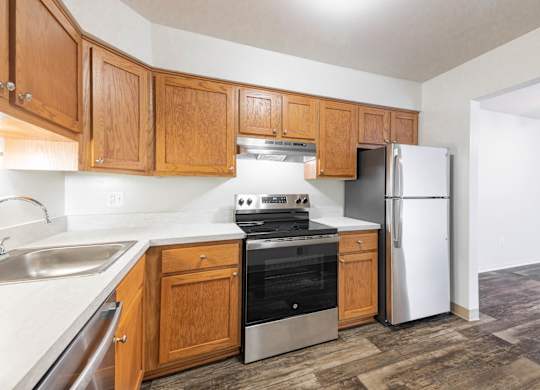 A kitchen with wooden cabinets and a stainless steel refrigerator.