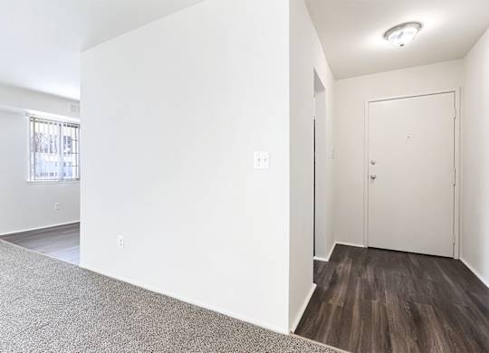 A room with a white door and a window with a view of a building outside.
