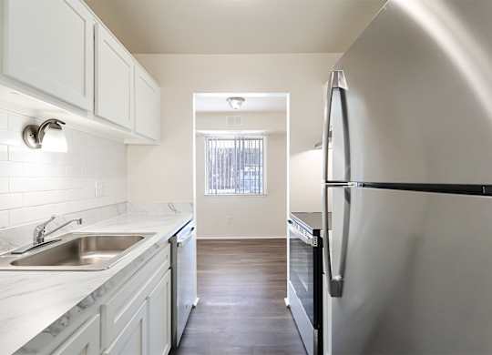 A kitchen with white cabinets and a black fridge.