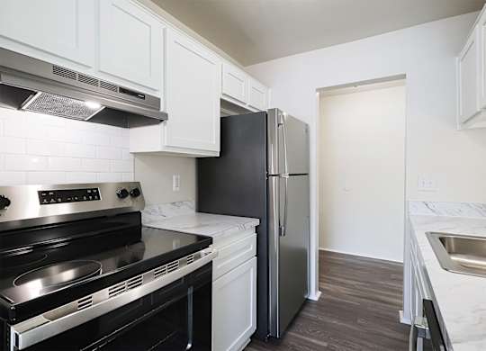 A kitchen with a black fridge and stove top oven.