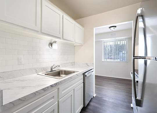 A kitchen with white cabinets and a marble countertop.
