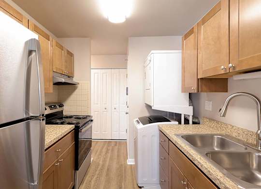 A kitchen with a refrigerator, sink, and cabinets.