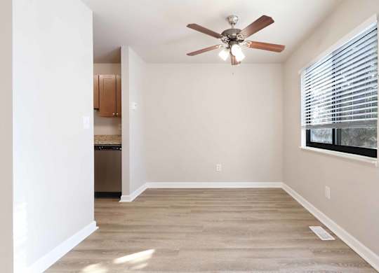 A room with a ceiling fan and a window with blinds.