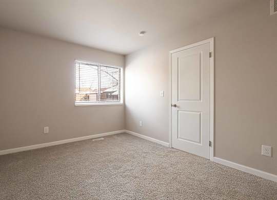 A room with a carpeted floor and a window with blinds.