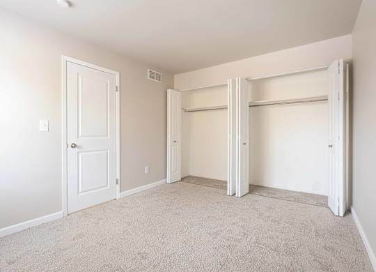 A room with a white door and a white closet with a white door.