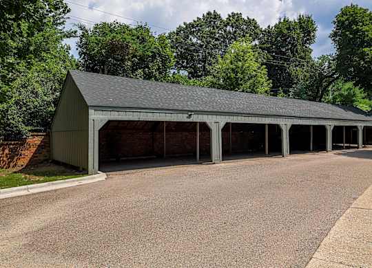 A large garage with a brick wall on the side is surrounded by trees.