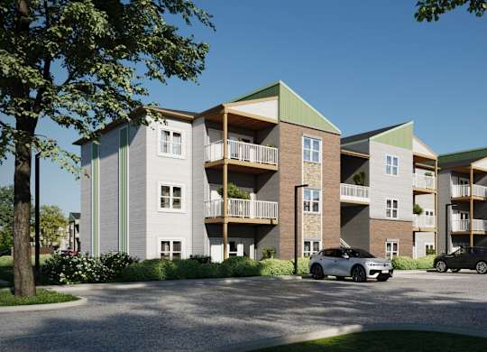 A modern apartment complex with cars parked in front.
